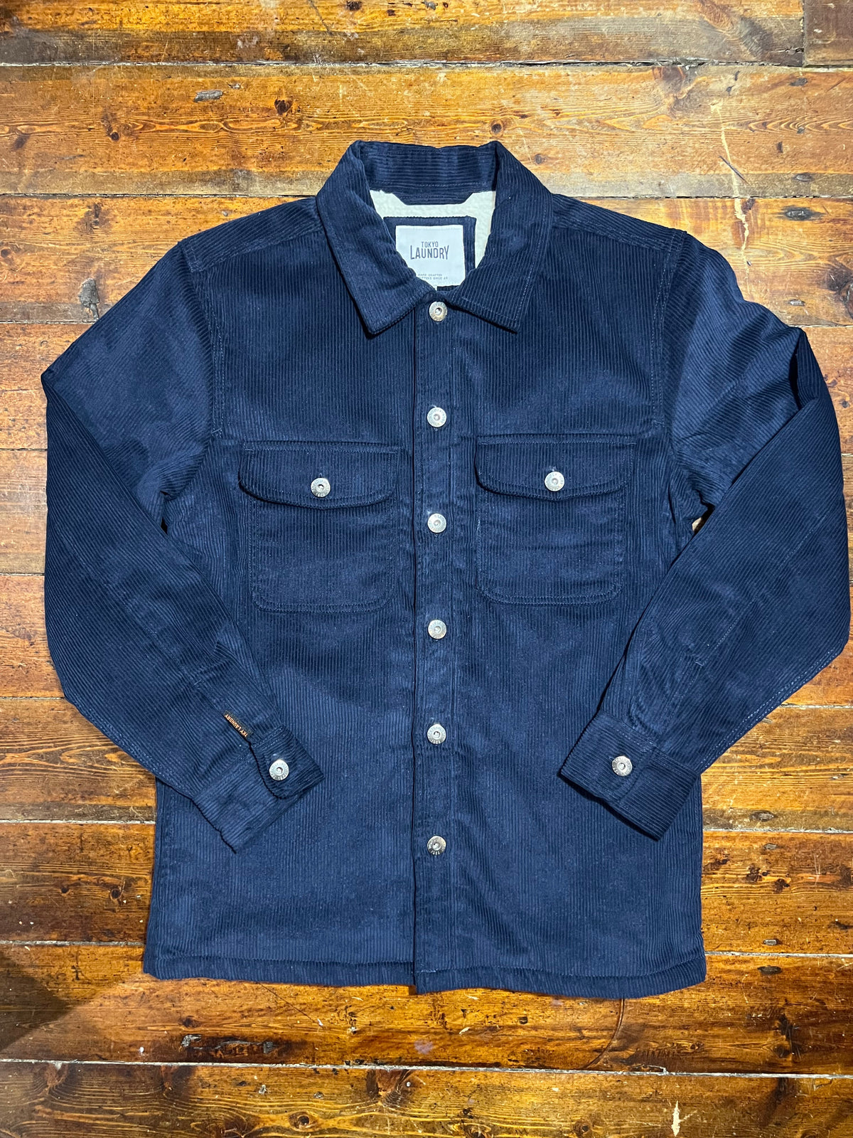 Cropley navy corduroy jacket shown on a hanger, featuring a classic collar and textured fabric for a stylish casual look.