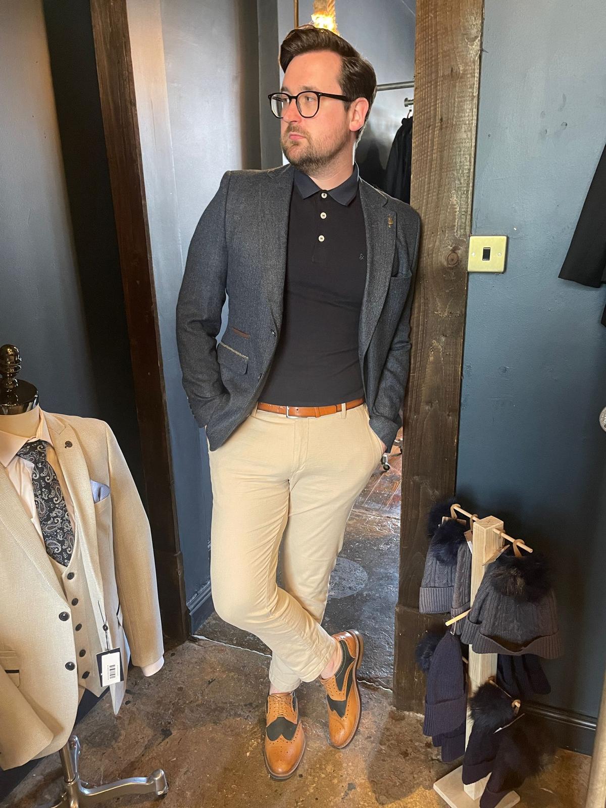 Dressing in a black blazer a blue shirt brown pants and a black bow tie  a young businessman wearing sunglasses is standing outside and taking a  break  Taking Break  Stock